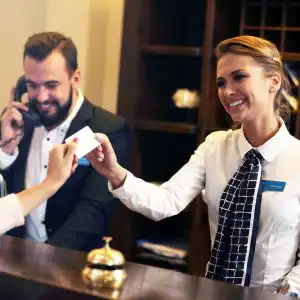 Due receptionist sorridenti dietro al bancone accolgono i clienti in hotel e gestiscono il check-in.