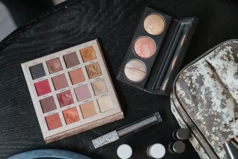 Palette di ombretti e polveri make-up professionali su tavolo nero, utile per spiegare la differenza tra cosmetica naturale e cosmetica di sintesi.