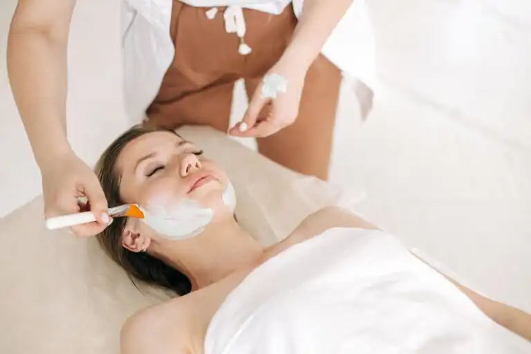 Estetista che applica una maschera viso con pennello durante un trattamento professionale, esempio delle nuove tendenze estetiche e digitali del 2025.cosmetologia digitale