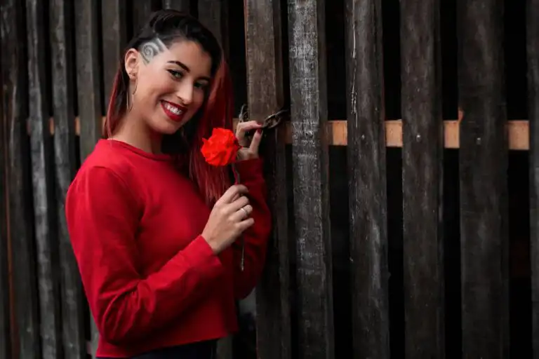 Donna sorridente con una rosa rossa, simbolo di forza e empowerment femminile.